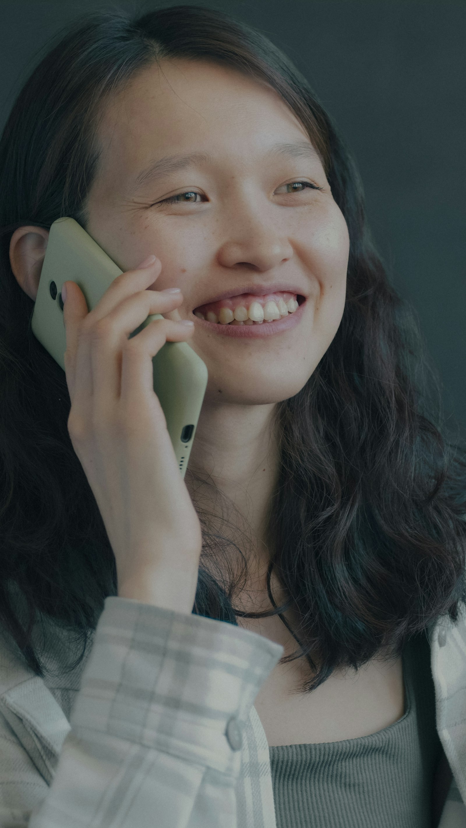 A smiling Asian woman talking on the phone