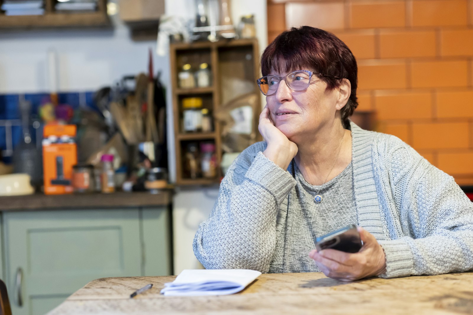 An Asian shop owner using a phone in her shop
