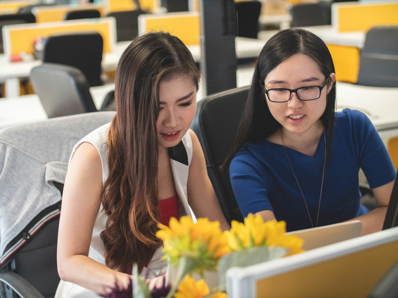 Two Asian women working together at a laptop