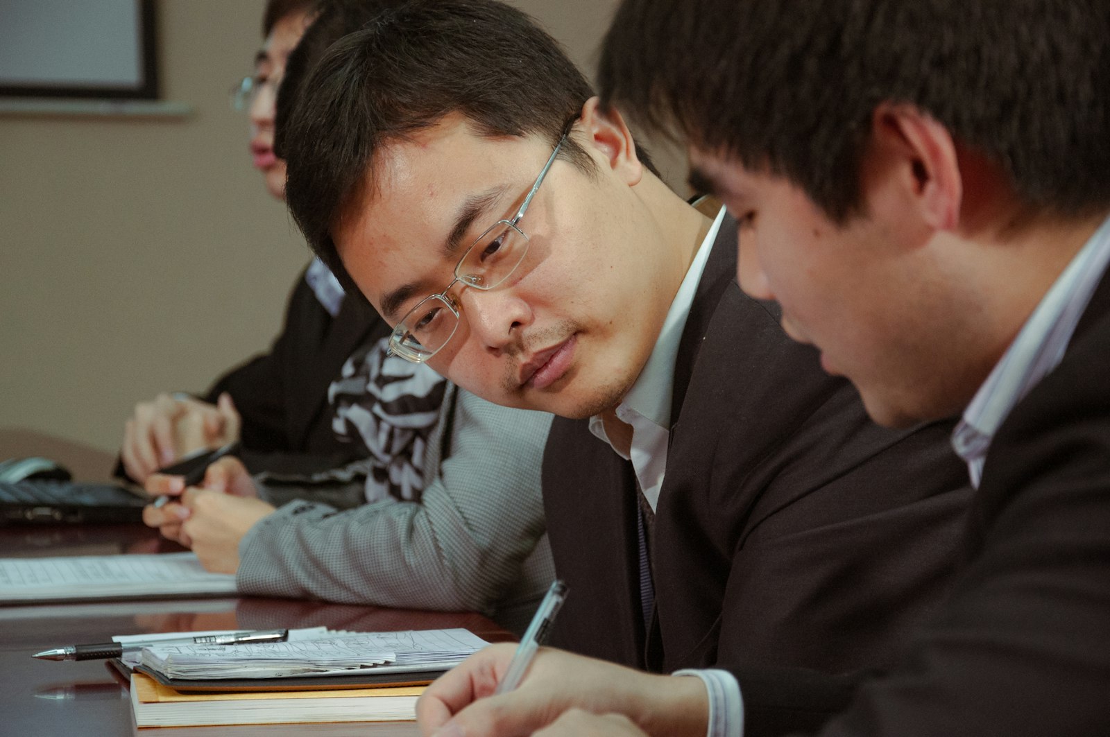 Asian officers in a meeting taking notes