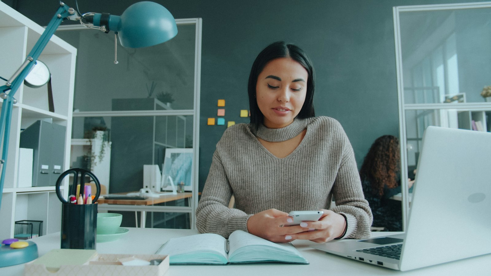 An Asian woman using a smartphone at her desk