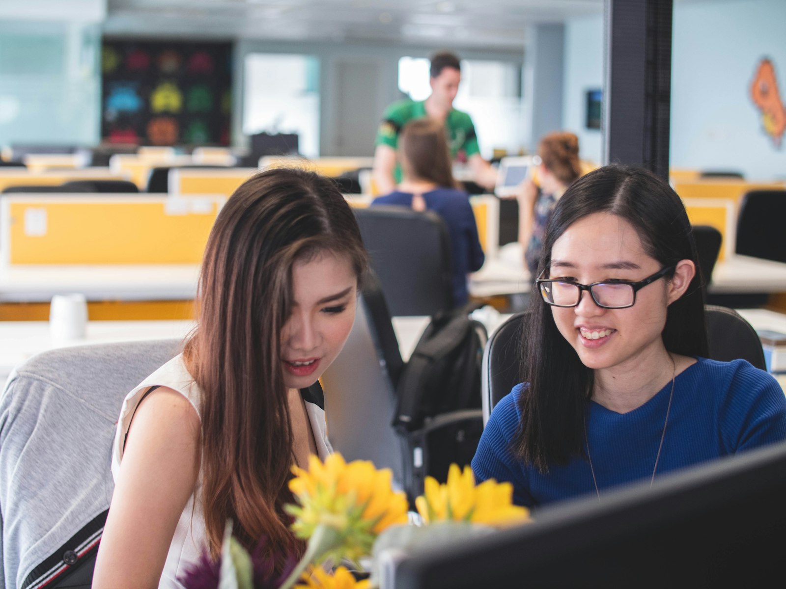 Two Asian women smiling in front of a computer screen