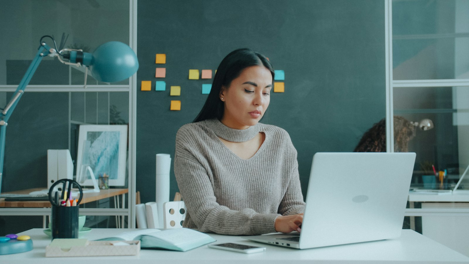 An Asian woman working on a laptop in an office