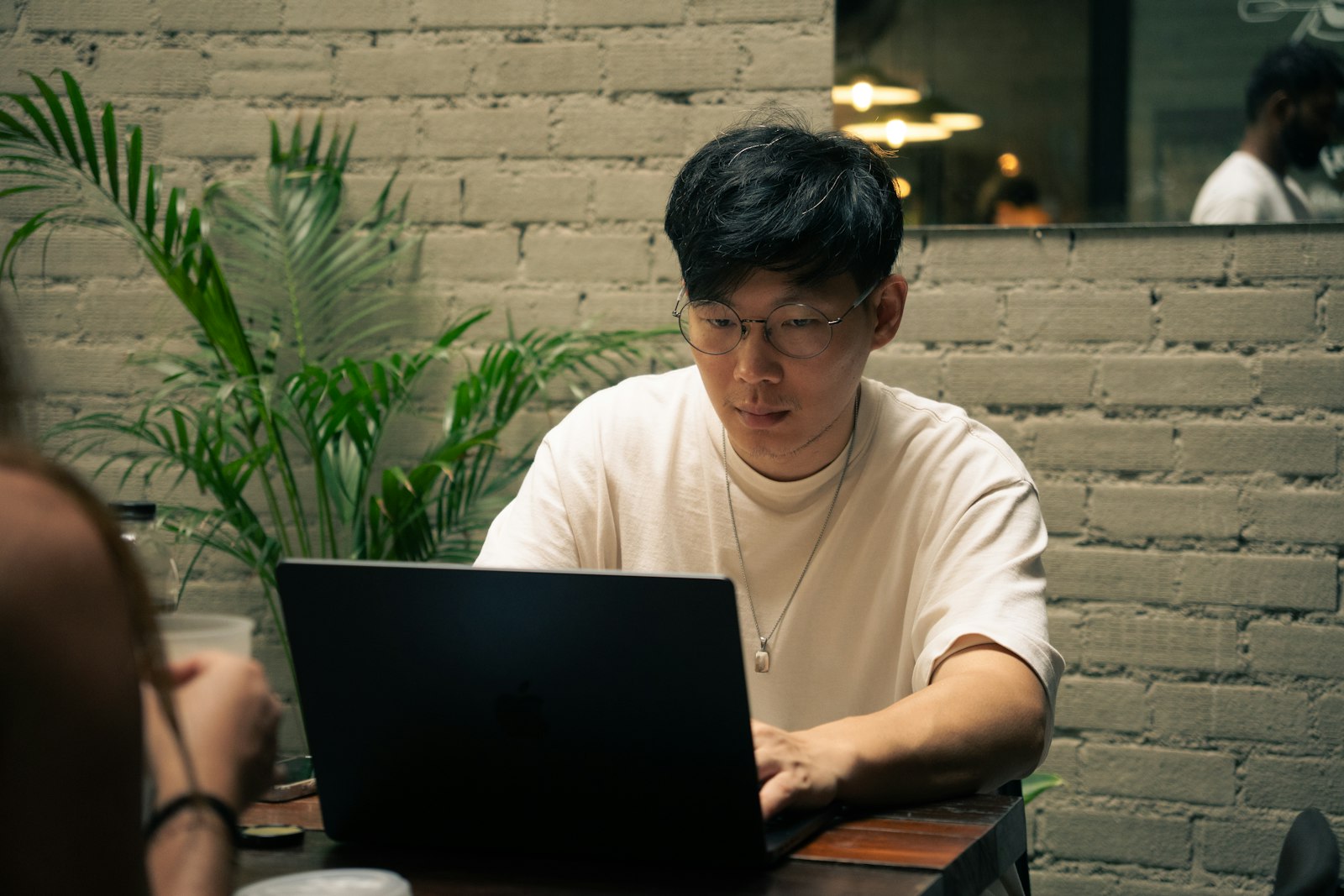An Asian man working on a laptop in a café