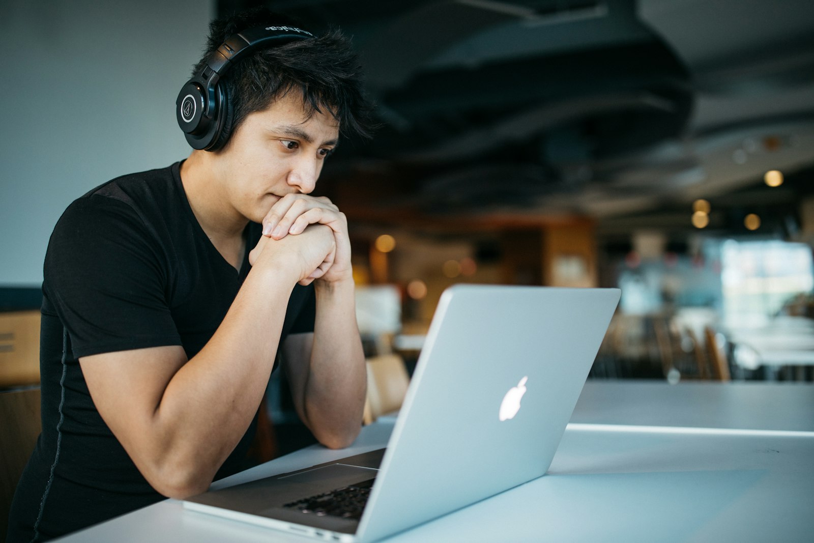 An Asian officer with headphones working on a laptop
